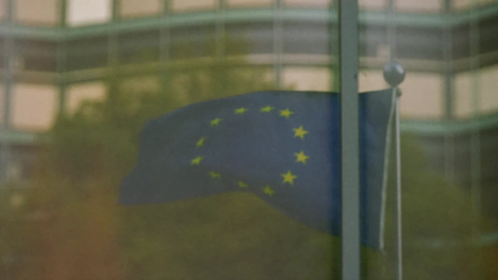 Bandera europea reflejada en la fachada acristalada de un edificio institucional