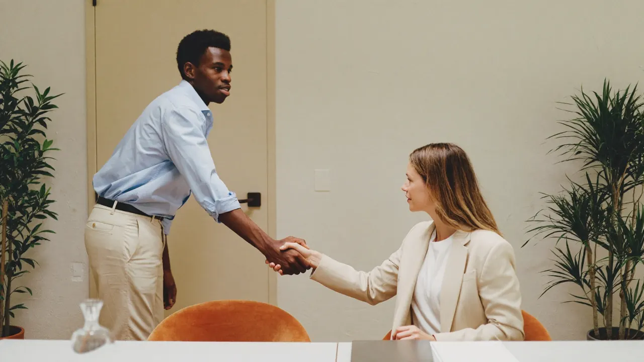 Dos personas se dan la mano sobre una mesa de reuniones